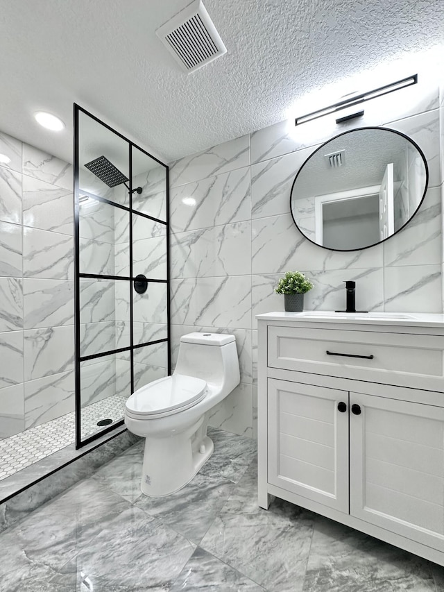 bathroom with toilet, vanity, a textured ceiling, and tiled shower