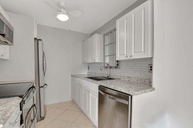 kitchen featuring sink, stainless steel appliances, white cabinets, backsplash, and light tile patterned flooring