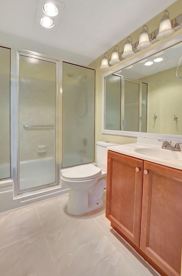 bathroom with vanity, toilet, and a shower with door