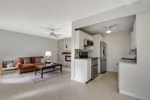 4064 Newport Q Unit 4064, Deerfield Beach, FL 33442 - kitchen with stainless steel appliances, ceiling fan, open floor plan, white cabinets, and a fireplace