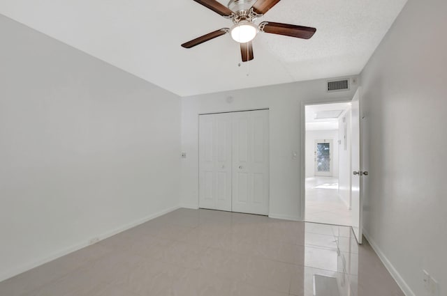 unfurnished bedroom featuring ceiling fan, light tile patterned flooring, and a closet