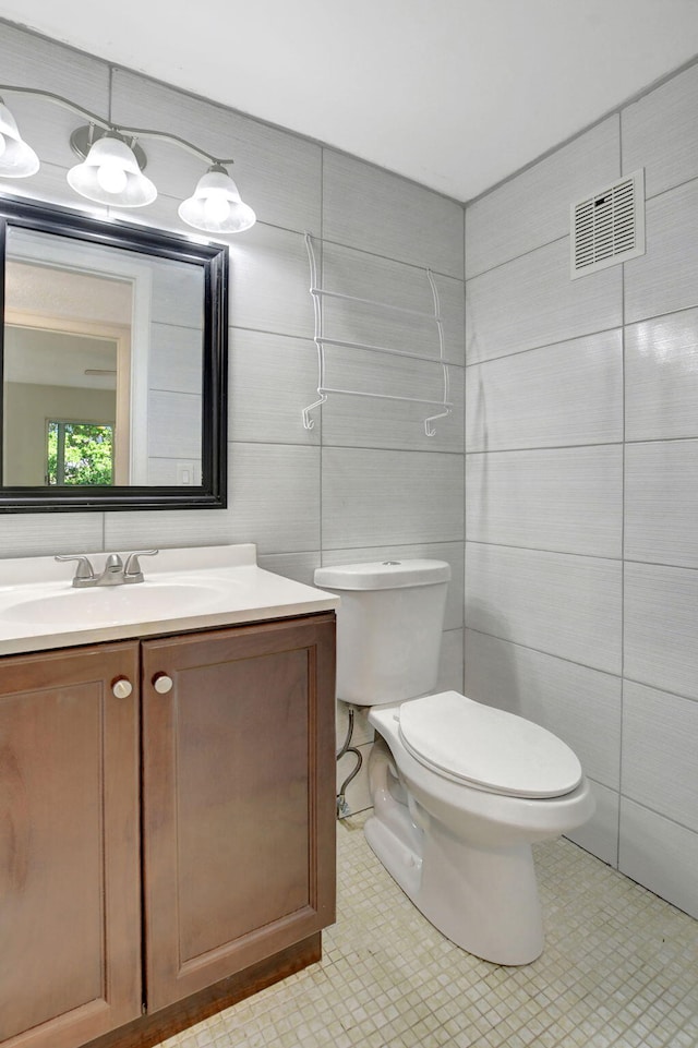 bathroom featuring vanity, tile walls, and toilet