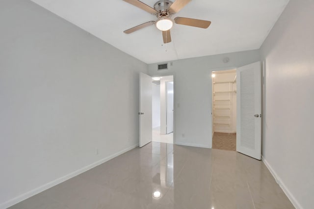 unfurnished bedroom featuring light tile patterned floors, a closet, a spacious closet, and ceiling fan