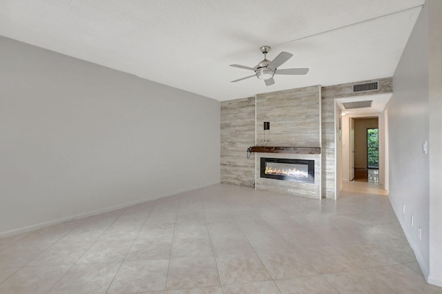 unfurnished living room with ceiling fan, light tile patterned flooring, and a tile fireplace