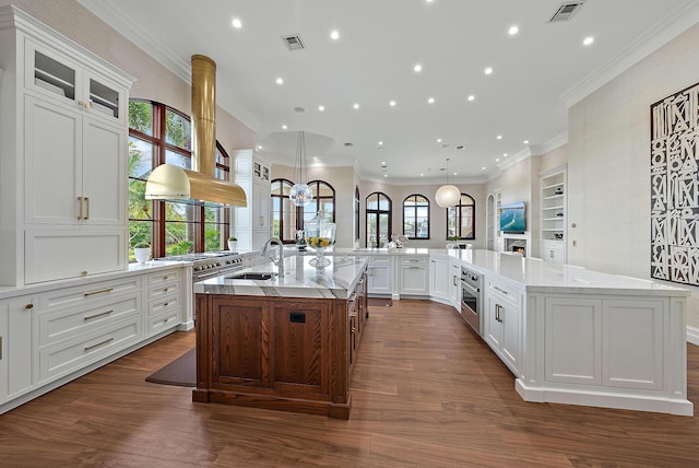 kitchen with a large island, pendant lighting, white cabinetry, stainless steel appliances, and light stone counters