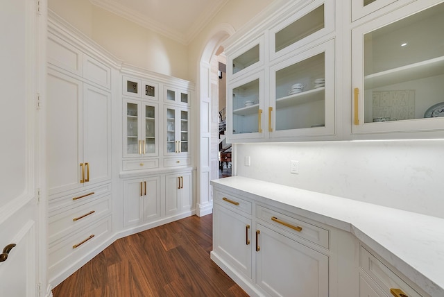 bar featuring dark wood-type flooring, crown molding, and white cabinets