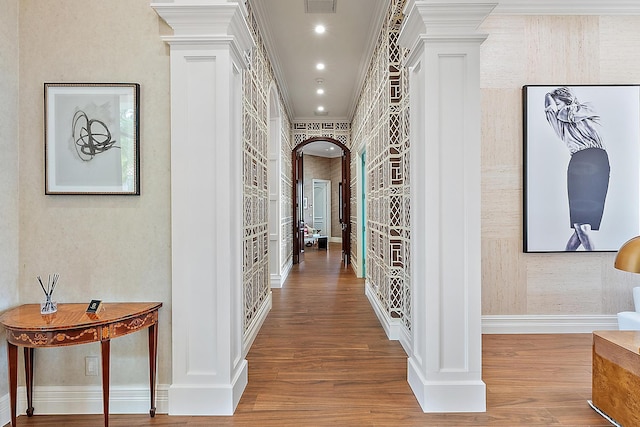 hallway with crown molding, hardwood / wood-style floors, and ornate columns