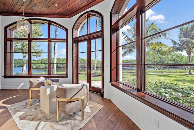 sunroom with a water view, wood ceiling, french doors, and a notable chandelier