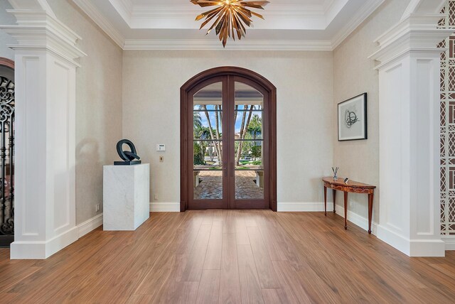 foyer entrance featuring a notable chandelier, wood-type flooring, french doors, and a raised ceiling