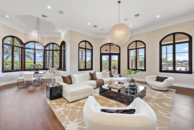 living room featuring an inviting chandelier, crown molding, light hardwood / wood-style flooring, and a high ceiling