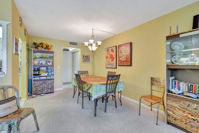 carpeted dining area featuring a textured ceiling and a chandelier