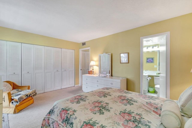 bedroom featuring connected bathroom and light colored carpet