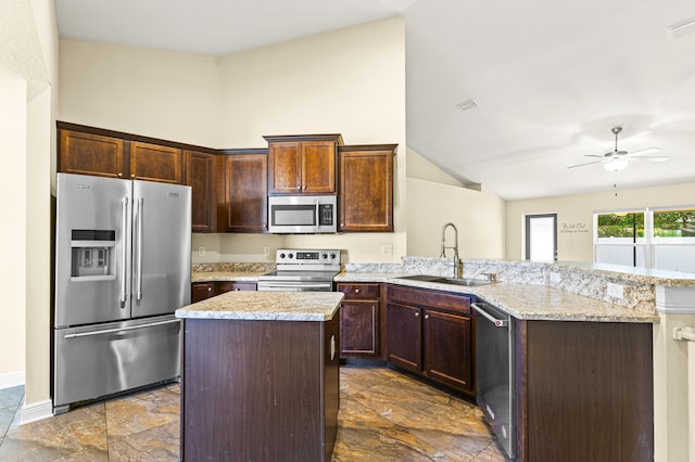 kitchen with ceiling fan, sink, stainless steel appliances, light stone counters, and kitchen peninsula