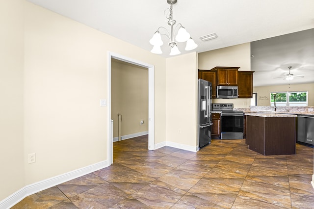 kitchen featuring appliances with stainless steel finishes, ceiling fan with notable chandelier, a center island, hanging light fixtures, and lofted ceiling