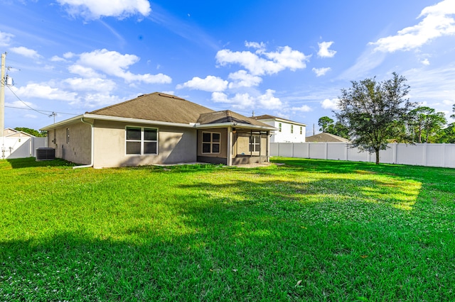 rear view of house with a sunroom, a yard, and central AC unit