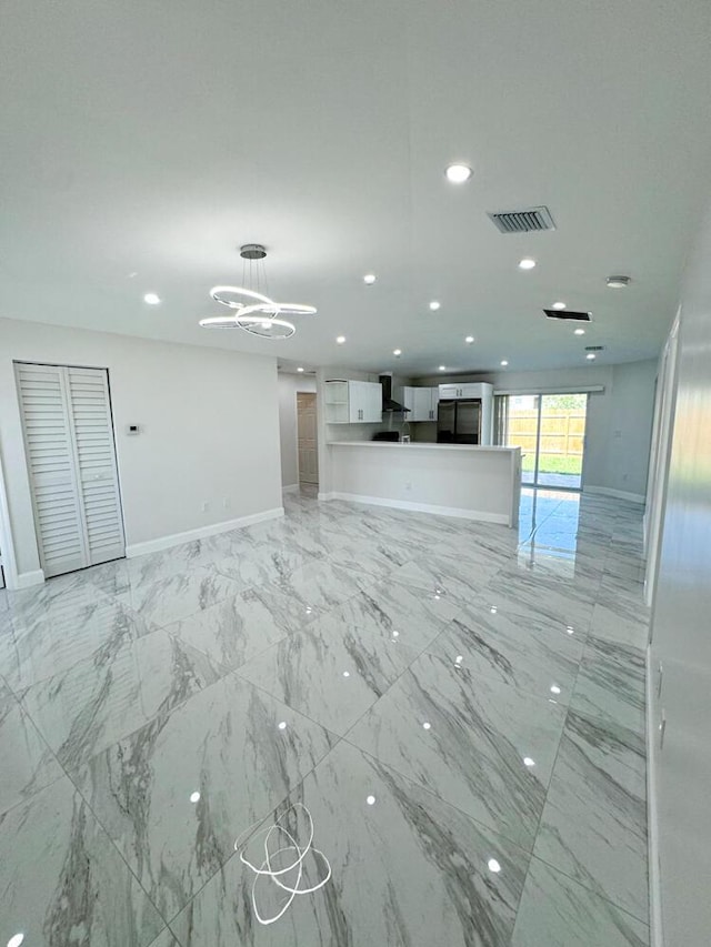 unfurnished living room featuring a chandelier