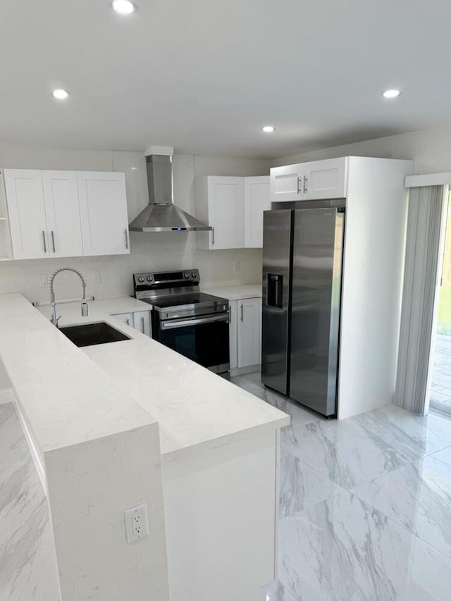 kitchen featuring sink, stainless steel appliances, wall chimney range hood, tasteful backsplash, and white cabinets