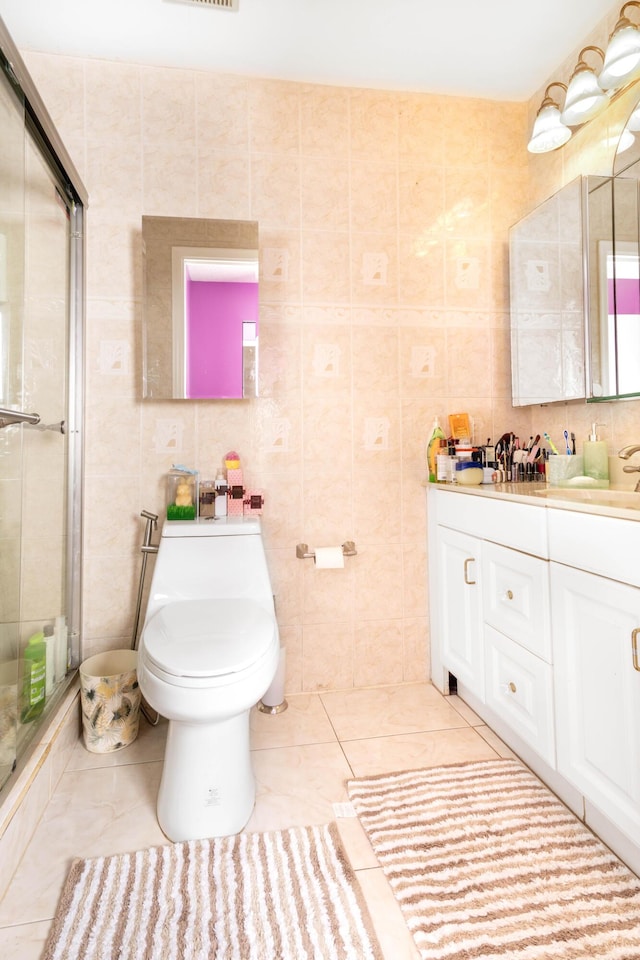 bathroom with tile patterned floors, a shower with door, tile walls, and toilet