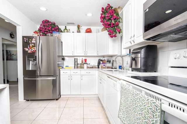 kitchen with white cabinetry, sink, stainless steel appliances, decorative backsplash, and light tile patterned floors