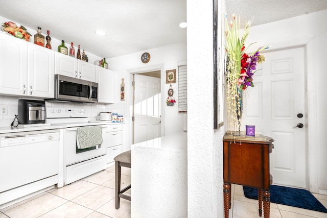 kitchen featuring white dishwasher, white cabinets, electric stove, decorative backsplash, and light tile patterned flooring