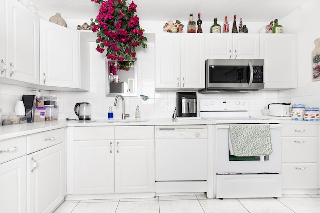 kitchen featuring dishwasher, backsplash, range, sink, and white cabinetry