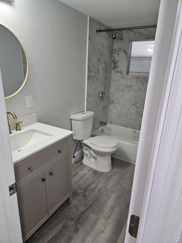 full bathroom with hardwood / wood-style floors, a textured ceiling, toilet, vanity, and tiled shower / bath