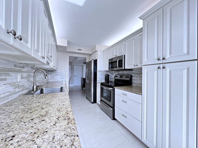 kitchen featuring decorative backsplash, appliances with stainless steel finishes, light stone counters, and sink