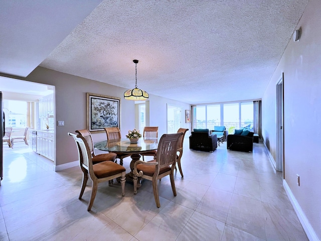 tiled dining space featuring a textured ceiling and expansive windows