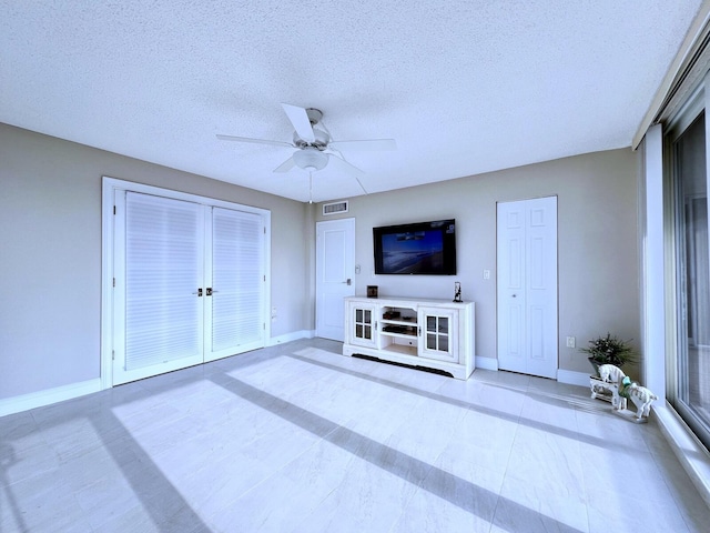 unfurnished living room featuring a textured ceiling and ceiling fan