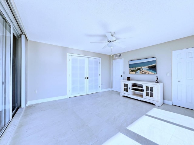 unfurnished living room with ceiling fan and a textured ceiling