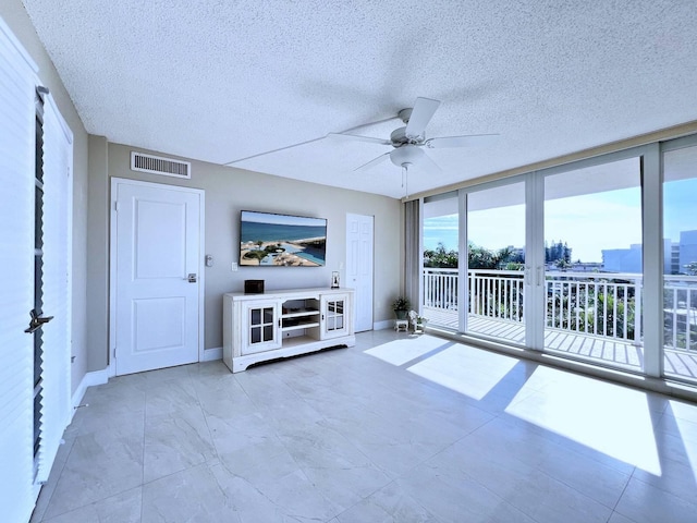 living room featuring ceiling fan, expansive windows, and a textured ceiling