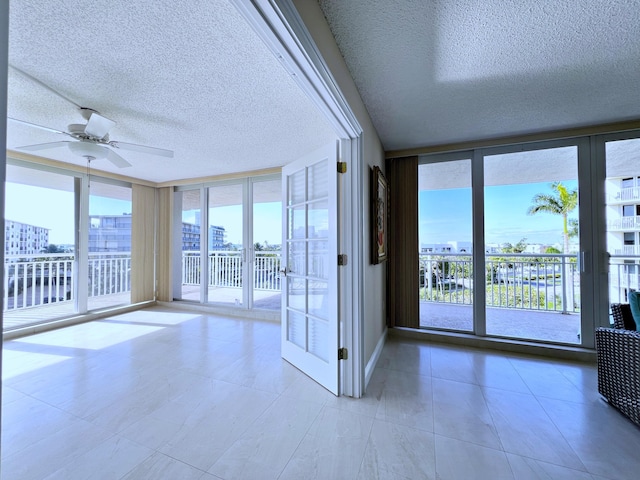 unfurnished sunroom featuring ceiling fan and a water view