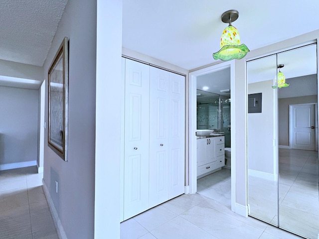 corridor with light tile patterned flooring, a textured ceiling, and electric panel