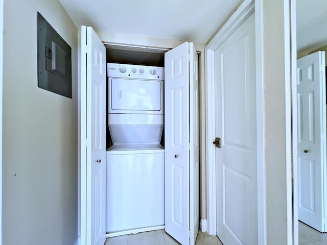 laundry room featuring light tile patterned floors, electric panel, and stacked washer / dryer