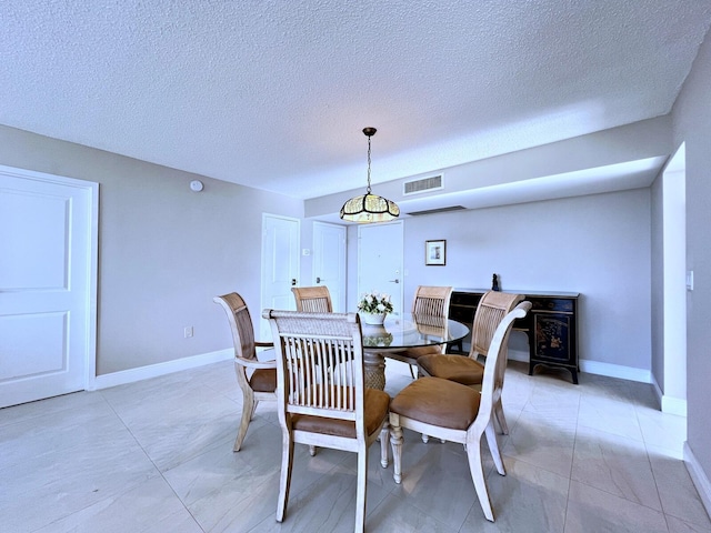 dining area with a wood stove and a textured ceiling