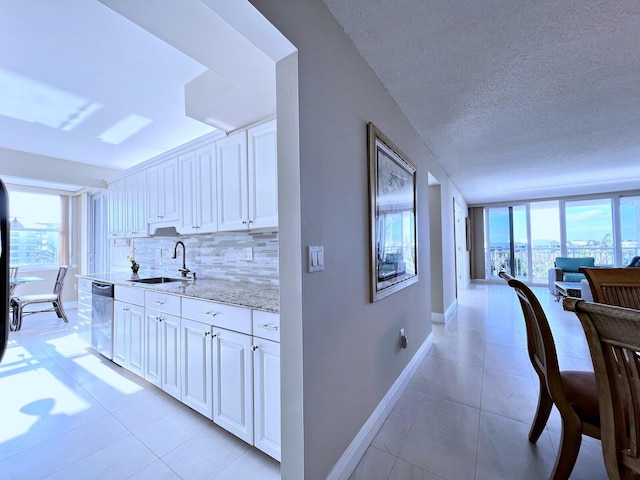 hall featuring light tile patterned floors, plenty of natural light, and sink