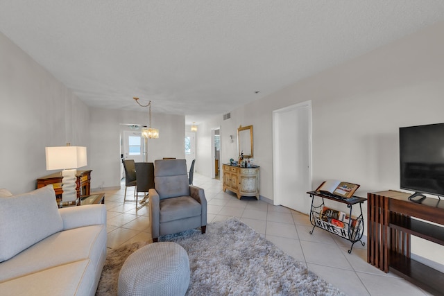 living room featuring a textured ceiling, light tile patterned floors, and a notable chandelier