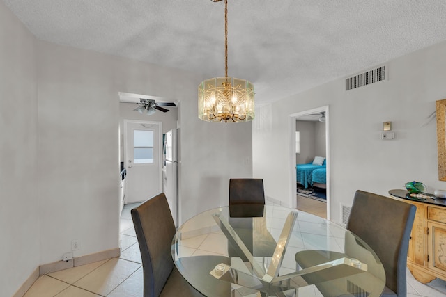 tiled dining space featuring ceiling fan with notable chandelier and a textured ceiling