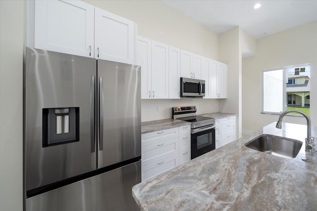 kitchen with white cabinetry, sink, light stone counters, and appliances with stainless steel finishes