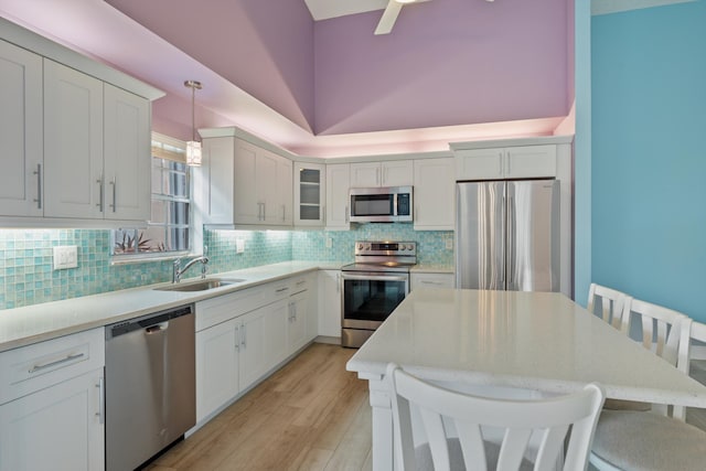 kitchen with a kitchen bar, sink, white cabinetry, hanging light fixtures, and stainless steel appliances