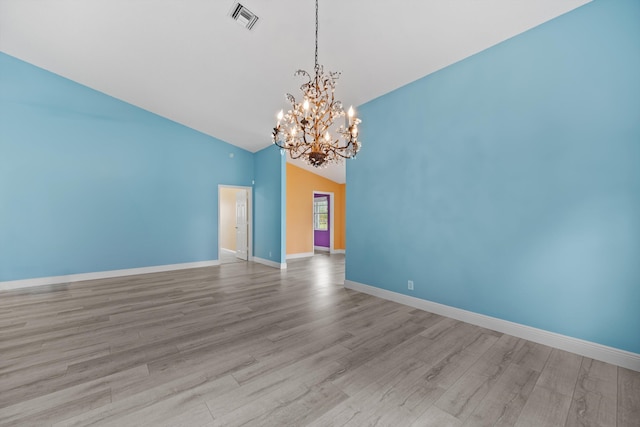 unfurnished room featuring lofted ceiling, a notable chandelier, and light hardwood / wood-style floors