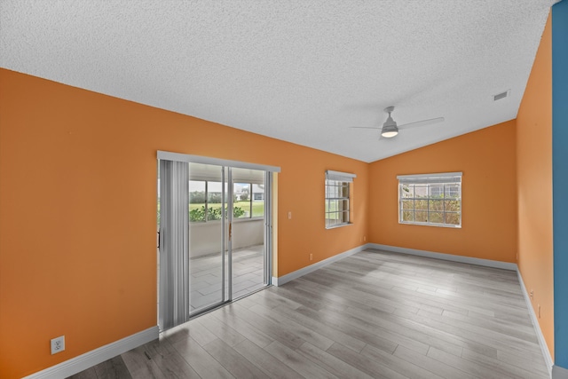 spare room with lofted ceiling, a textured ceiling, light hardwood / wood-style floors, and ceiling fan