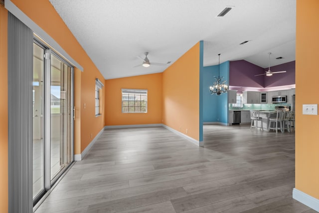 corridor featuring an inviting chandelier, vaulted ceiling, and light hardwood / wood-style flooring