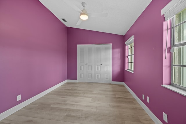 unfurnished bedroom with multiple windows, ceiling fan, vaulted ceiling, and a closet