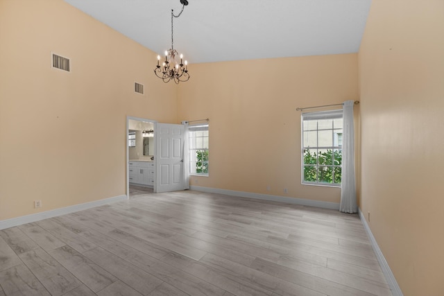 spare room featuring plenty of natural light, light wood-type flooring, and a notable chandelier