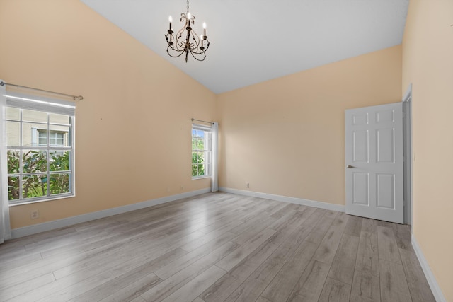 empty room featuring an inviting chandelier, high vaulted ceiling, and light hardwood / wood-style floors