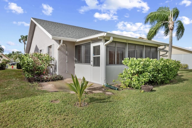 view of property exterior featuring a sunroom and a lawn