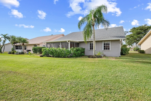 rear view of property featuring a sunroom and a lawn