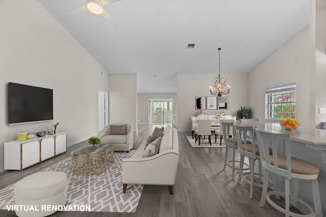 living room featuring hardwood / wood-style floors, ceiling fan with notable chandelier, a wealth of natural light, and vaulted ceiling