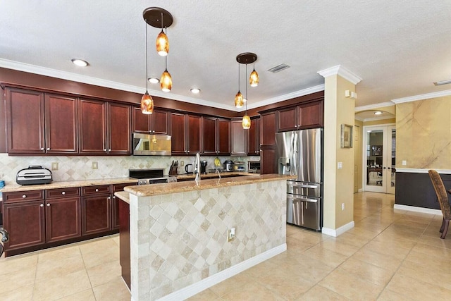 kitchen with light stone countertops, stainless steel appliances, crown molding, pendant lighting, and an island with sink